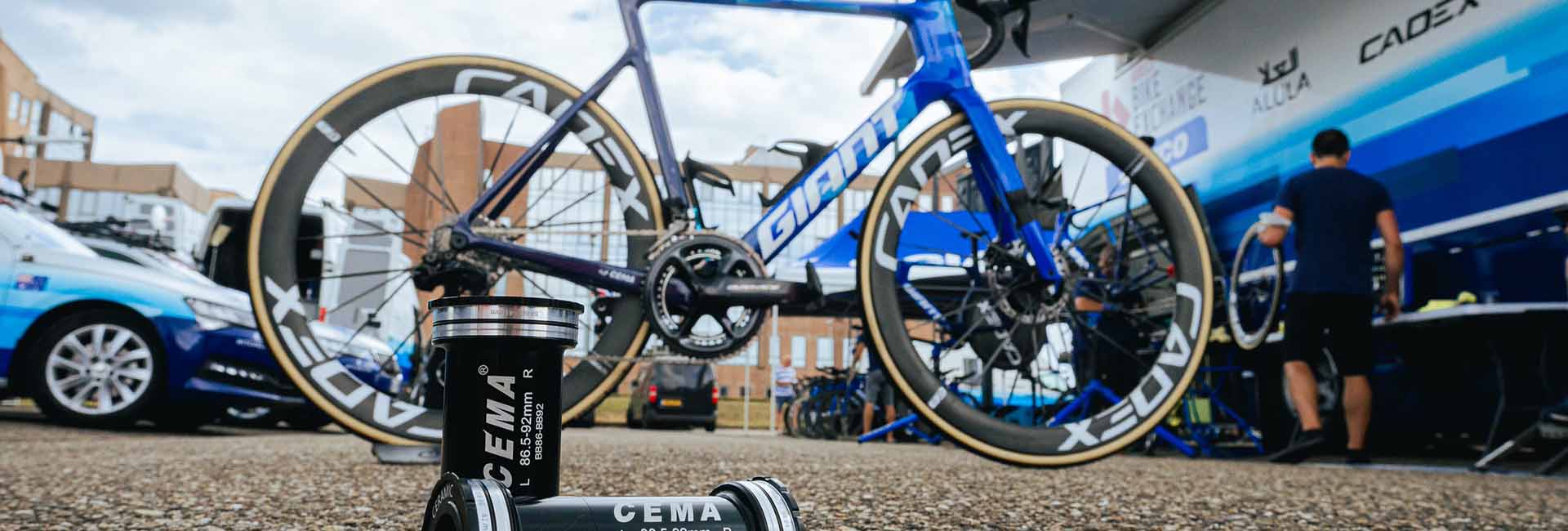 Vélo de route Giant avec roues Cadex devant un bus d’équipe cycliste, mis en avant avec boîtiers de pédalier céramique CEMA au premier plan